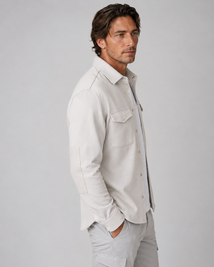 A man wearing a Buki Atlas Over Shirt in Birch  button-up shirt. Great for travel, and eveeryday.
