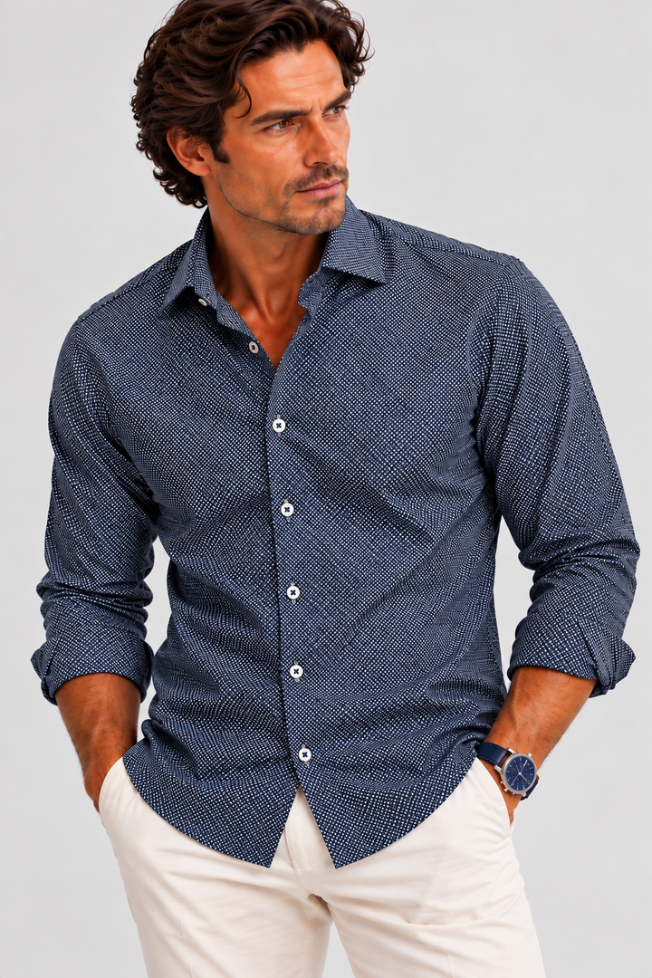 A man wearing a Buki Studio Dot long-sleeve button-down shirt with a subtle textured pattern in Navy, paired with dark navy pants, photographed against a solid gray studio background.