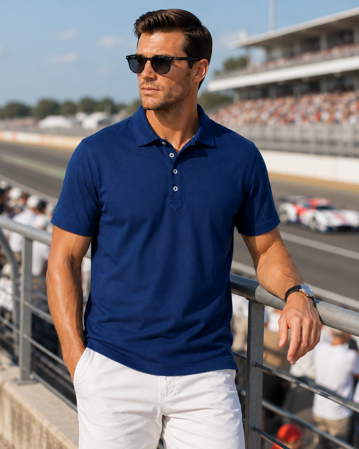Man wearing a navy Cinqo polo shirt and white Eagle shorts at a race track.