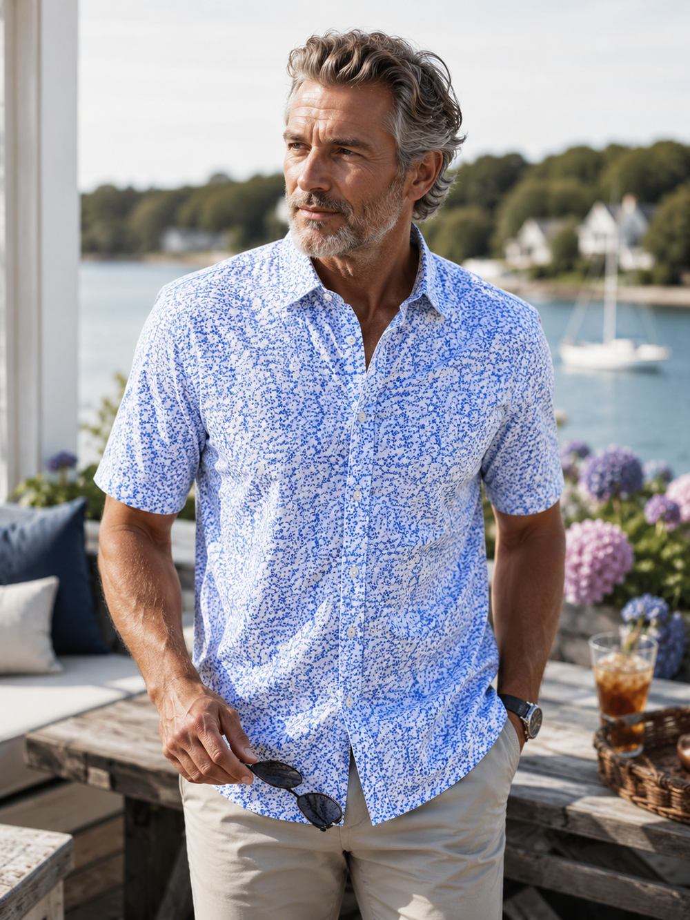 Man wearing a Five O'Floral Short Sleeve shirt by a waterfront with boats and greenery.
