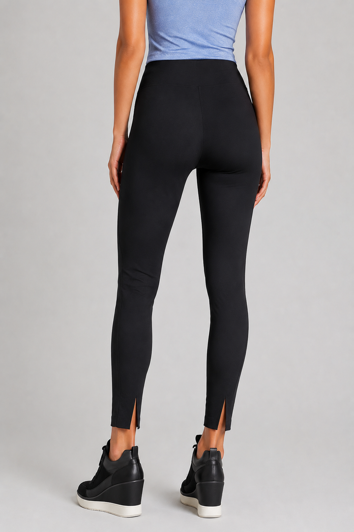 Person wearing black rise and shine leggings with cutouts on a gray background