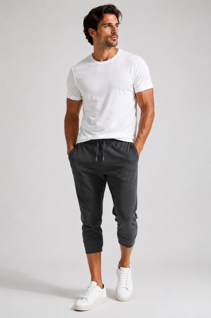 A man modeling a white Cinqo short-sleeve crewneck t-shirt and dark gray Scrimmage jogger pants with white sneakers, standing against a light gray studio background.