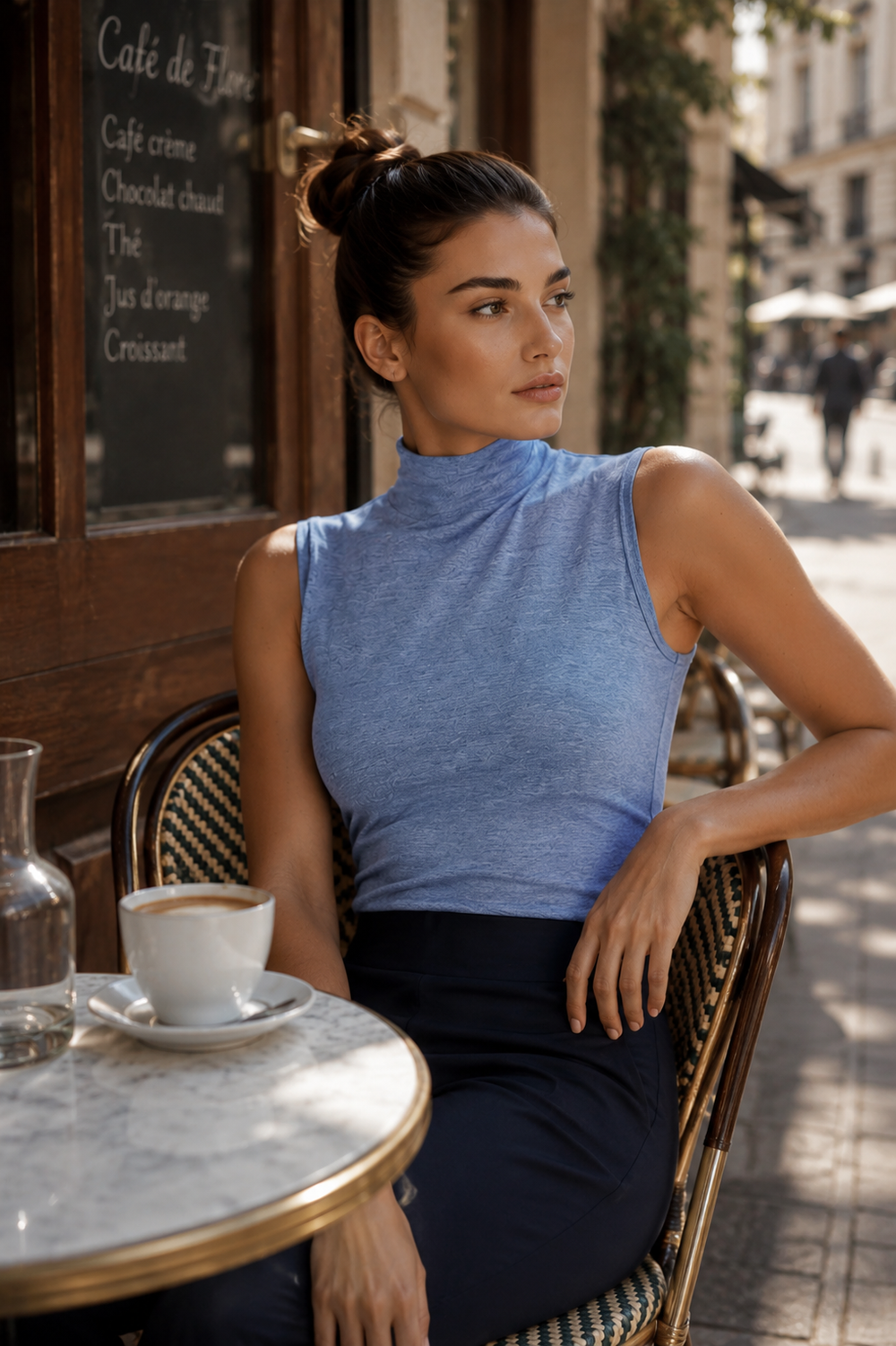 Woman sitting at a cafe table in an urban setting in Buki Sleeveless Turtleneck and Marta Pant