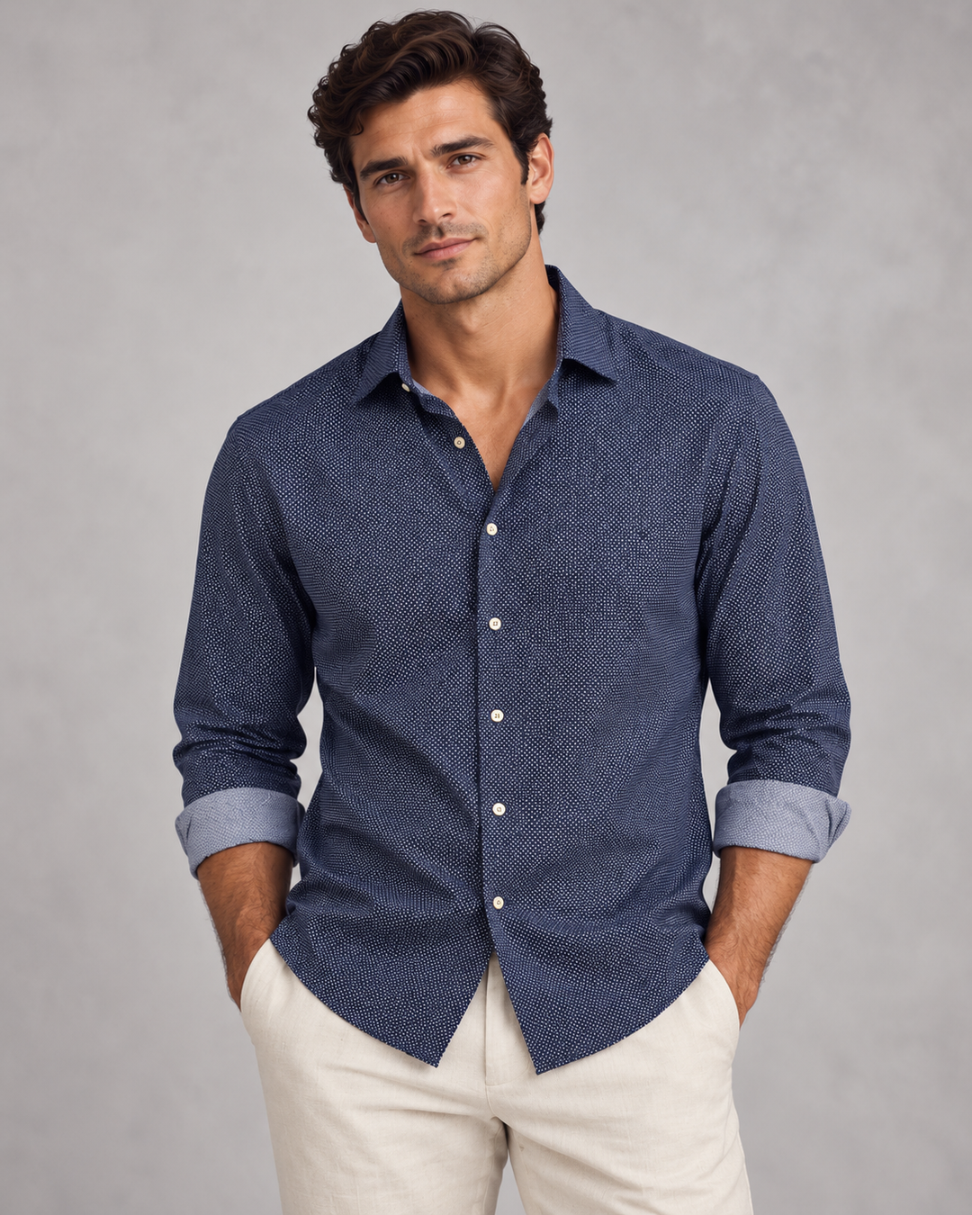 A man wearing a Buki Studio Dot long-sleeve button-down shirt with a subtle textured pattern in Navy, paired with dark navy pants, photographed against a solid gray studio background.