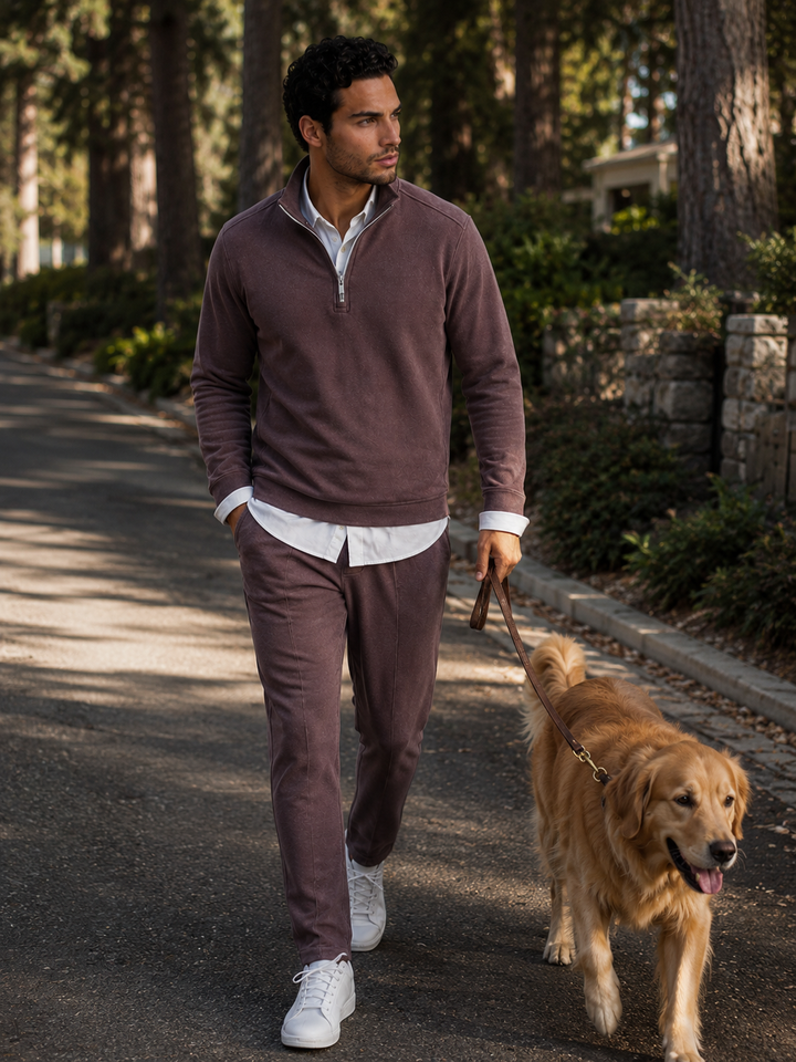 Man walking a dog on a path in a park-like setting wearing a Voey Quarter Zip with Espresso Getaway Pant walking a dog