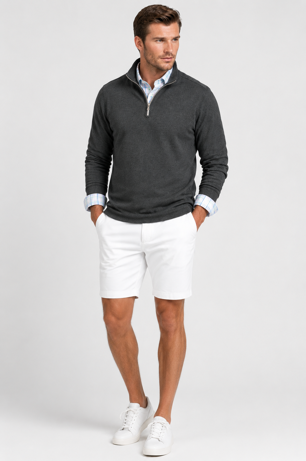 Man wearing a dark gray Voey quarter-zip sweatshirt, Pacific Grid Tech dress shirt, white Eagle shorts, and white sneakers on a light gray background.
