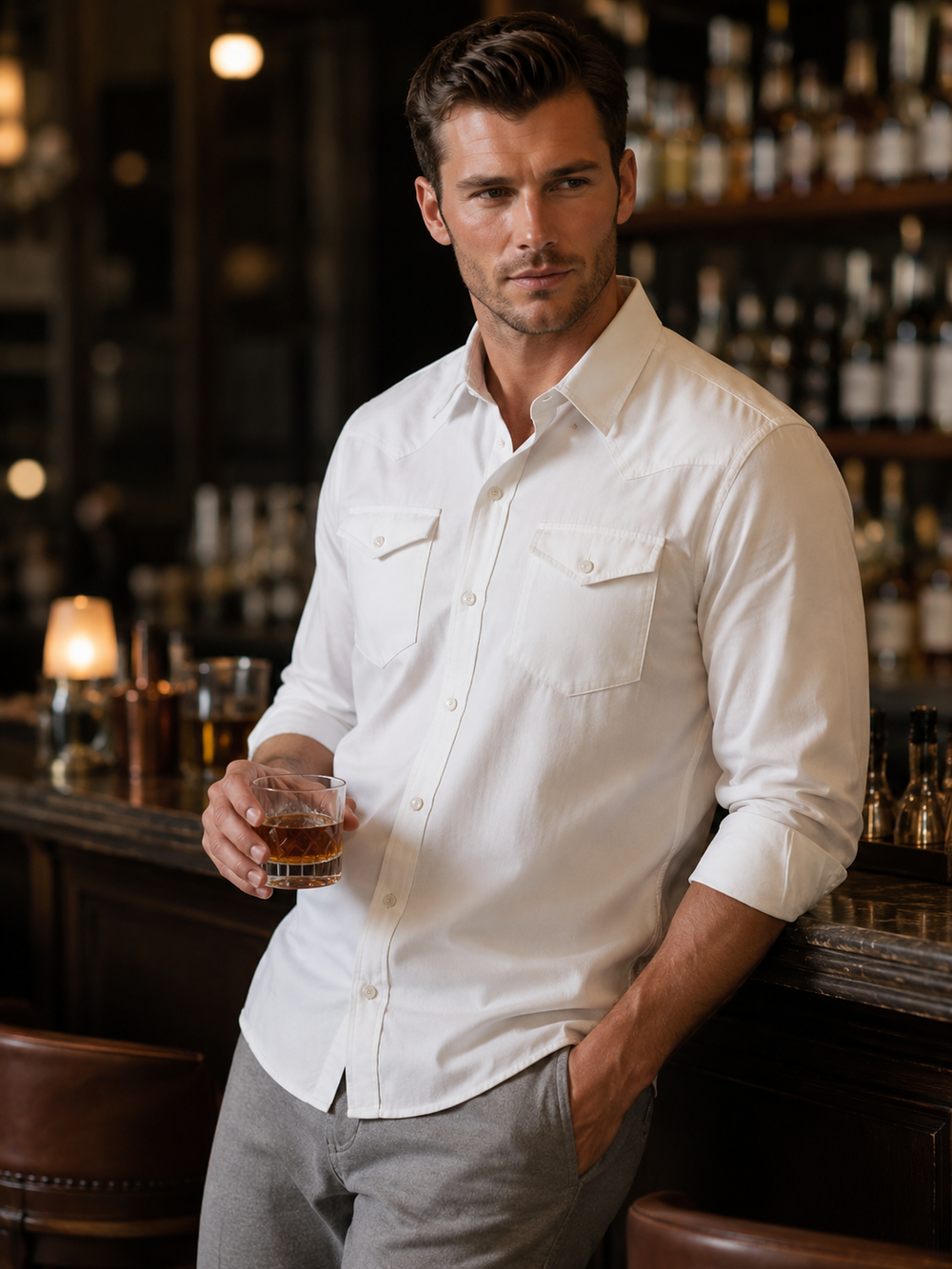 Man in a white Western Tech shirt holding a glass in a bar setting